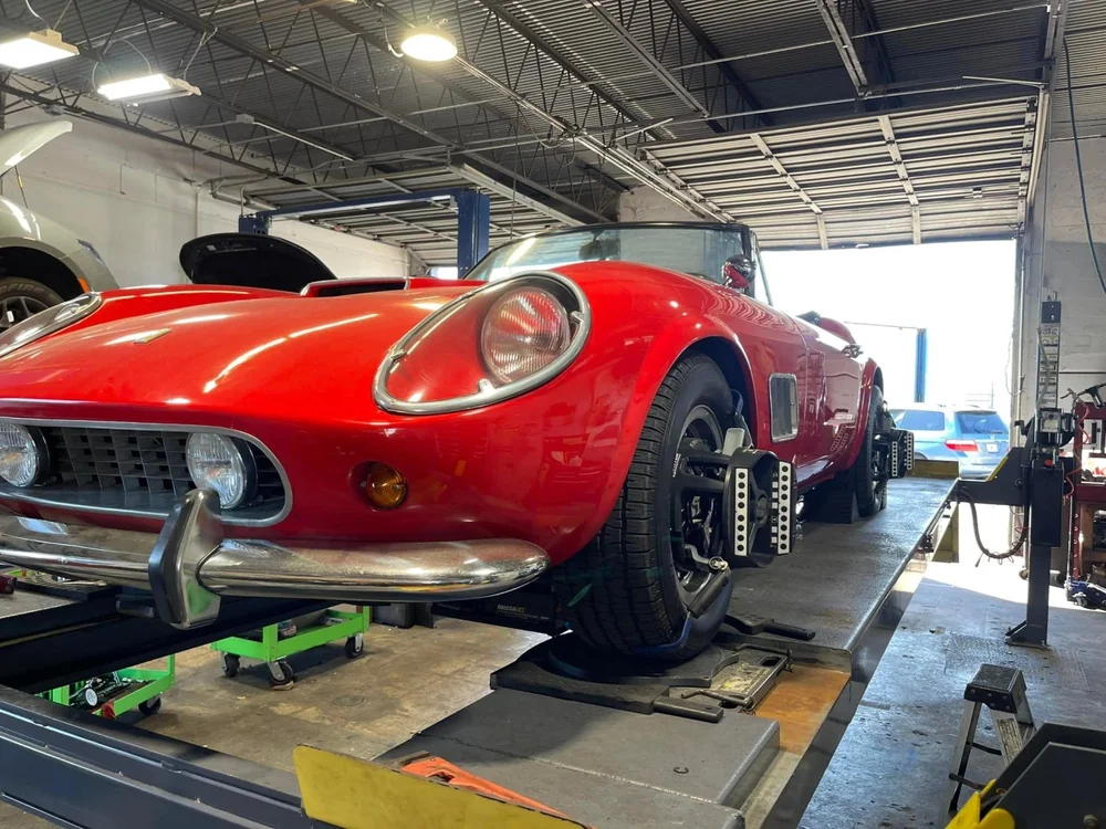 Classic red sports car raised on a lift at Jupiter Car-Care