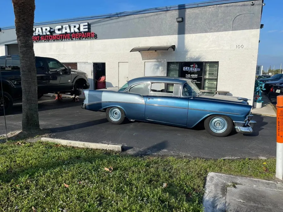 Classic blue car parked in front of the Jupiter Car-Care shop
