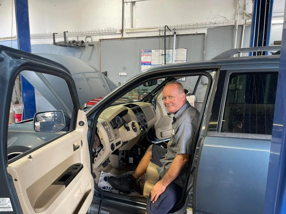 Technician working inside a vehicle cab during diagnosis at Jupiter Car-Care in Jupiter