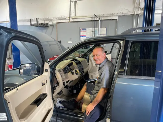 Technician working inside a vehicle cab during diagnosis at Jupiter Car-Care in Jupiter