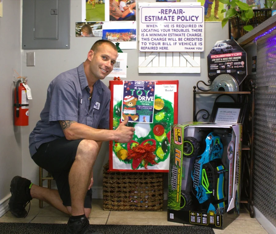 A Jupiter Car-Care team member with donated toys inside the shop