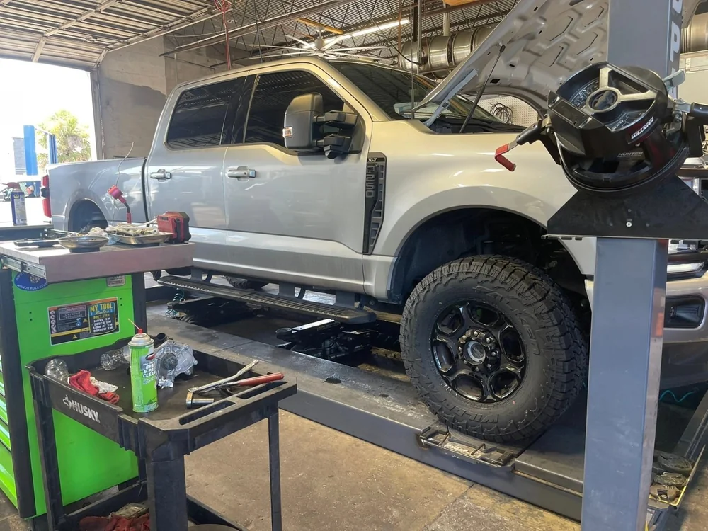 Pickup truck raised on a lift during maintenance at Jupiter Car-Care in Jupiter